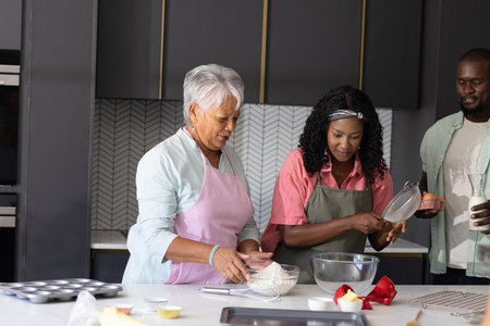 Baking together in modern kitchen, African American family smiling, three generations. bonding, generational, happiness, culinary, lifestyle, togethernessの写真素材