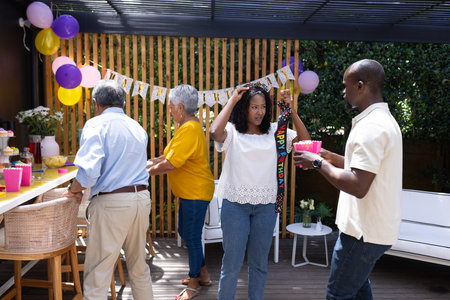 Celebrating birthday outdoors, family decorating with balloons in festive atmosphere. Celebration, party, decorations, happiness, festivity, gatheringの写真素材