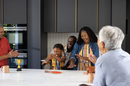 Celebrating victory at home, African American parents and child smiling joyfully. Family, happiness,...