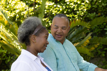 In park, African American senior couple talking surrounded by lush greenery. Relaxation, nature, outdoors, elderly, communication, bondingの写真素材