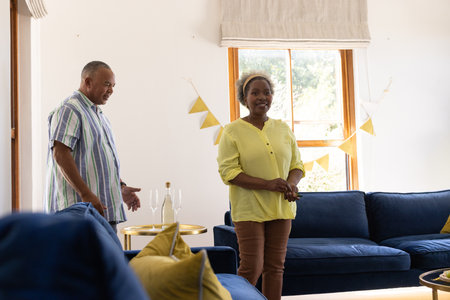 African American senior couple enjoying conversation in bright, cozy living room. happiness, lifestyle, indoors, domestic, retirement, relationshipの写真素材
