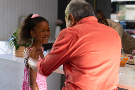 Grandfather and granddaughter sharing joyful moment together in modern kitchen. Family, bonding, generation, happiness, lifestyle, togethernessの写真素材
