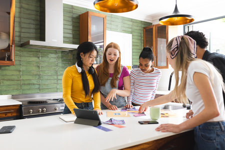 In school, teenagers collaborating on creative project using tablet and photos. Collaboration,...