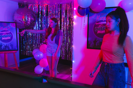 Teen girls enjoying disco-themed birthday party with vibrant lights and decorations. Celebration,...