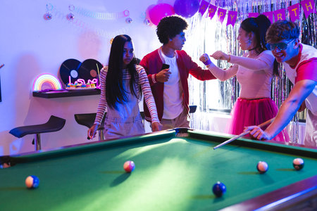 Teenagers playing pool and celebrating birthday in colorful party room. Celebration, billiards, fun, friends, joyful, leisureの写真素材