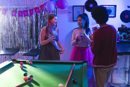 Teen friends celebrating birthday with drinks and laughter around pool table. Celebration, friendship, billiards, leisure, party, nightlifeの写真素材