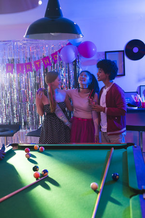 Teenagers celebrating birthday party near pool table, laughing and enjoying together. Celebration,...