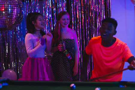 Teens enjoying lively birthday party with pool table and disco ball. celebration, vibrant,...