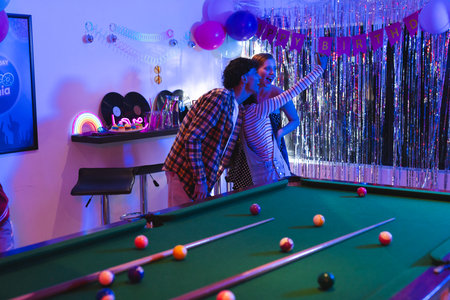Teens taking selfie at birthday party near pool table with festive decorations. Youth, celebration, friendship, fun, gathering, lifestyleの写真素材