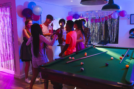Teens celebrating birthday around pool table with balloons and festive decorations. Celebration, teenagers, fun, party, billiards, gatheringの写真素材