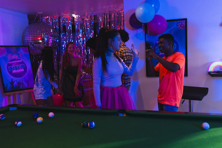 Teenagers dancing and celebrating party at home with balloons and pool table. celebration, fun, friends, gatheringの写真素材