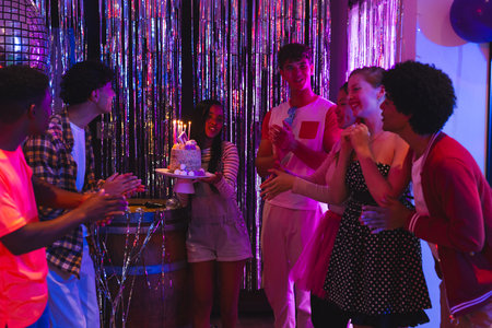 Teens celebrating birthday with cake and candles at vibrant party. Celebration, teenagers, joy, festivity, friendshipの写真素材