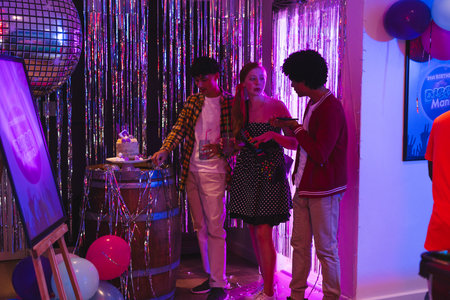 Teens celebrating at party with cake and balloons, enjoying festive atmosphere. Celebration,...