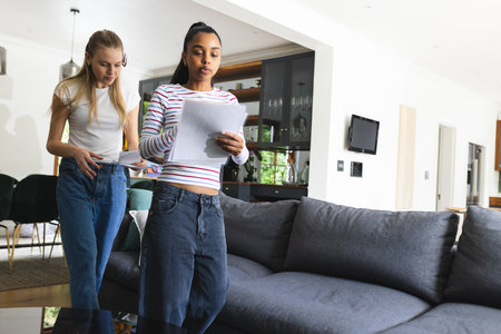 Teen girls reviewing documents at home, preparing for school project together. Homework,...