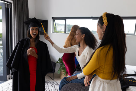 Friends celebrating graduation at home, smiling and enjoying special moment together. celebration, achievement, milestone, party, happiness, successの写真素材