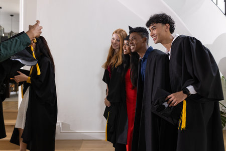Graduating students in caps and gowns posing happily for group photo. Graduation, ceremony, celebration, accomplishment, achievement, successの写真素材