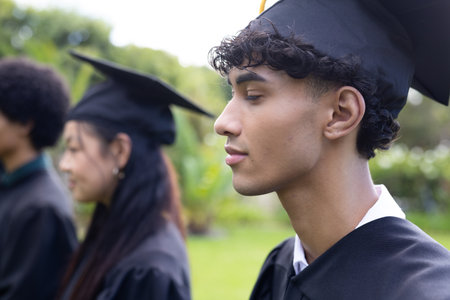 Graduating students in caps and gowns celebrating outdoors with joyful expressions. Graduation, celebration, achievement, academic, accomplishment, happinessの写真素材
