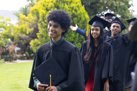 Celebrating outdoors, teens in graduation gowns with joyful expressions after school. ceremony, achievement, celebration, youth, accomplishment, happinessの写真素材