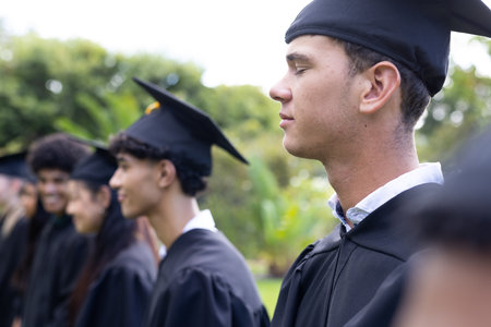 Graduating students in caps and gowns celebrating outdoors with joyful expressions. Graduation, celebration, achievement, ceremony, commencement, academicの写真素材
