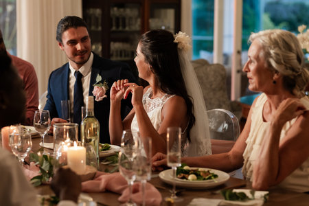 Bride and groom sharing joyful conversation with guests at elegant wedding dinner. celebration, romance, ceremony, reception, happiness, coupleの写真素材