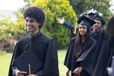 Graduating students in caps and gowns celebrating outdoors with joyful expressions. Graduation, celebration, achievement, ceremony, academic, successの写真素材
