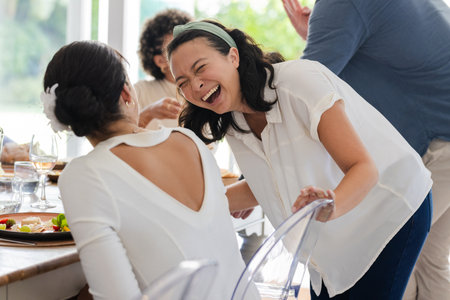 Guests laughing and enjoying conversation at wedding reception, celebrating together. Celebration, event, happiness, togetherness, friendship, laughterの写真素材