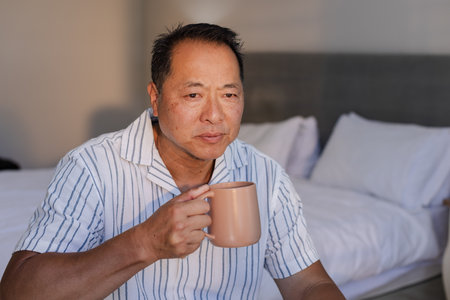 Relaxing at home, senior man enjoying morning coffee in cozy bedroom. Relaxation, coziness, morning routine, elderly, lifestyle, home interiorの写真素材