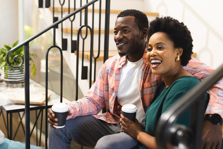 Smiling friends enjoying coffee together on staircase, sharing joyful conversation. Friendship, socializing, laughter, bonding, casual, relaxedの写真素材