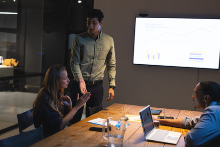In office, business professionals discussing data presentation during night meeting. teamwork,...