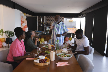 Family enjoying festive meal together, sharing stories and laughter at dining table. Celebration,...