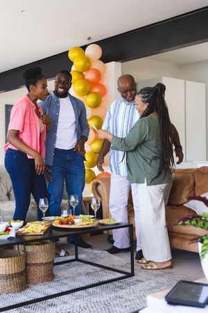 Family celebrating together at home, enjoying laughter and conversation with drinks. celebration,...