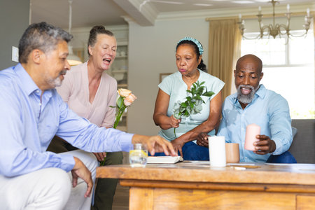 Seniors celebrating at home, sharing laughter and holding flowers and candles. Elderly, celebration,...