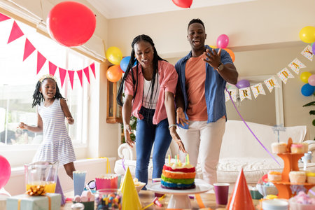 Celebrating birthday, African American family with colorful decorations and cake at home. Celebration, happiness, festive, cheerful, party, joyfulの写真素材