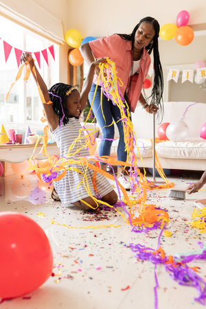 Celebrating birthday with colorful streamers, African American mother and child at home. Celebration, family, happiness, love, bonding, festiveの写真素材
