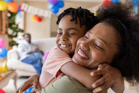 African American mother and child hugging joyfully at home during celebration. Family, love, happiness, festivity, embrace, togethernessの写真素材
