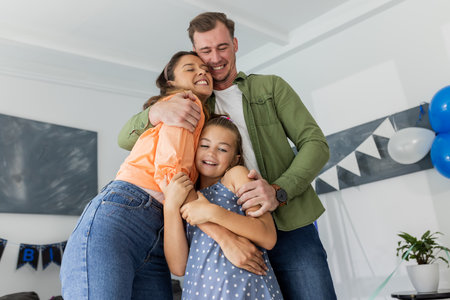 Family celebrating birthday at home, hugging joyfully with balloons and decorations. Celebration, happiness, togetherness, festiveの写真素材