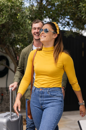 Couple enjoying vacation, walking outdoors with suitcase, smiling under sunny sky. Travel, adventure, tourism, holiday, destination, happinessの写真素材