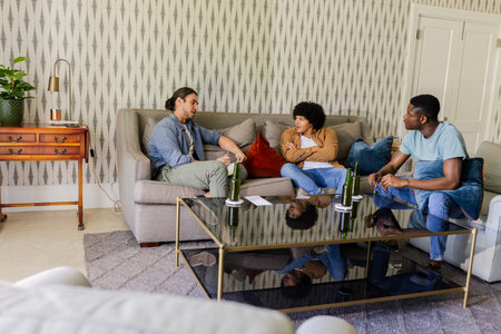 Friends relaxing on sofa, enjoying conversation with drinks in cozy living room. Friendship, relaxation, leisure, beverages, gathering, homeの写真素材