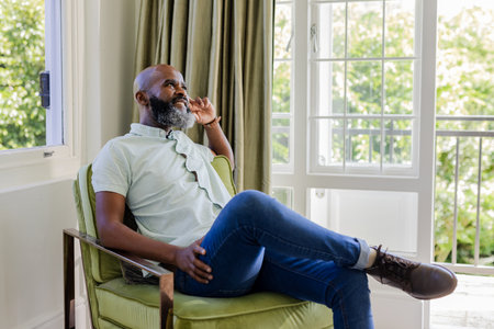 Relaxing in cozy chair, thoughtful man enjoying peaceful moment by window. Relaxation,...