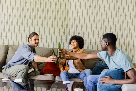 Friends celebrating with drinks on sofa, enjoying joyful moments together indoors. Celebration, friendship, bonding, fun, relaxation, gatheringの写真素材