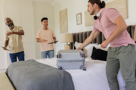 Packing suitcase in bedroom, friends sharing excitement and laughter for wedding. Travel, friendship, celebration, preparation, joy, anticipationの写真素材