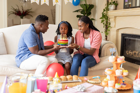 Celebrating birthday, happy family of three blowing candles on colorful cake at home. celebration,...