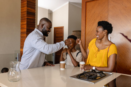 Family enjoying morning coffee together in kitchen, sharing happy fist bumps. togetherness, bonding, breakfast, lifestyle, celebration, happinessの写真素材