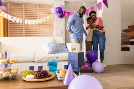 Family celebrating birthday at home, hugging and smiling with party decorations. Celebration, happiness, gathering, festiveの写真素材