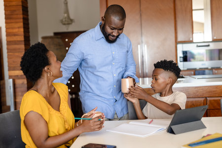 Family enjoying quality time at home, sharing drinks and using tablet together. togetherness, bonding, relaxation, technology, leisure, lifestyleの写真素材