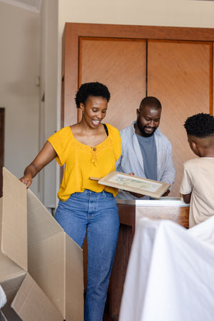 Family unpacking boxes at home, smiling and organizing new living space. moving, relocation,...