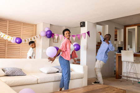 African American family celebrating at home with balloons and festive decorations. Celebration, party, happiness, joyful, togethernessの写真素材