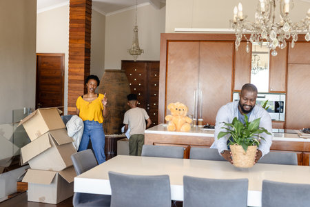 Family unpacking boxes in new home, arranging plants and organizing belongings. Moving, relocation,...
