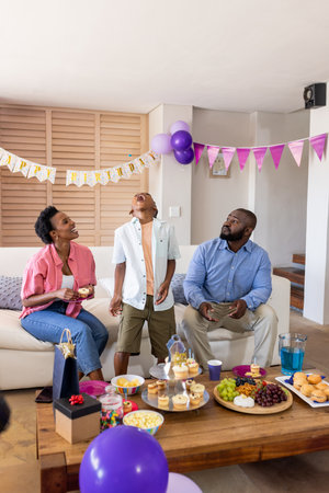 Family enjoying birthday celebration at home with snacks and colorful decorations. party, happiness,...