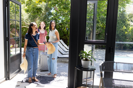 Arriving at sunny poolside villa, three young women express joyful surprise. Friends are ready for...